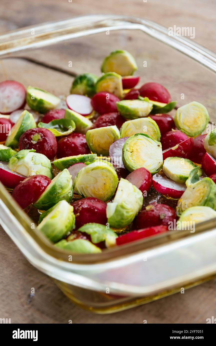 Brussels sprouts and radishes with some oil in a baking dish, ready to be roasted. Stock Photo