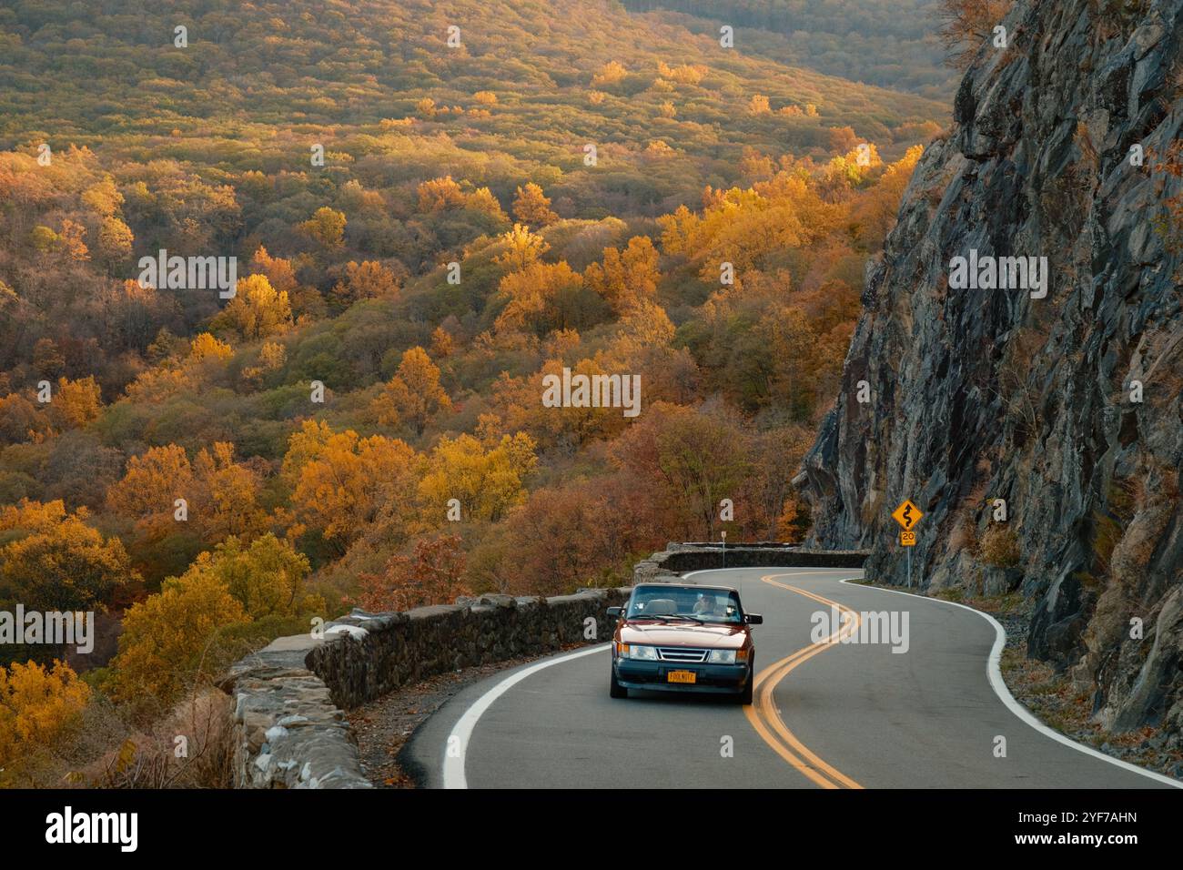 A car navigates the winding road through colorful fall foliage along ...