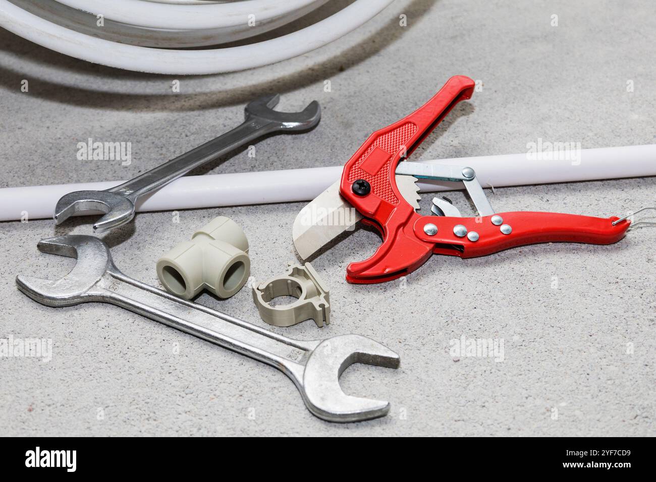 On the floor, there lies a pair of wrenches along with a pipe cutter, both essential tools used for various mechanical and plumbing tasks Stock Photo