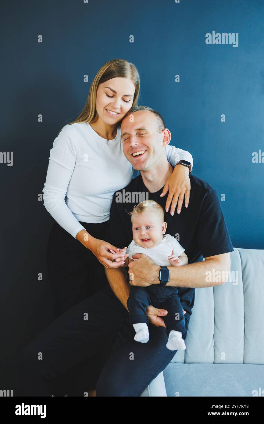 Cute young family mom dad and newborn baby smiling three of them at ...