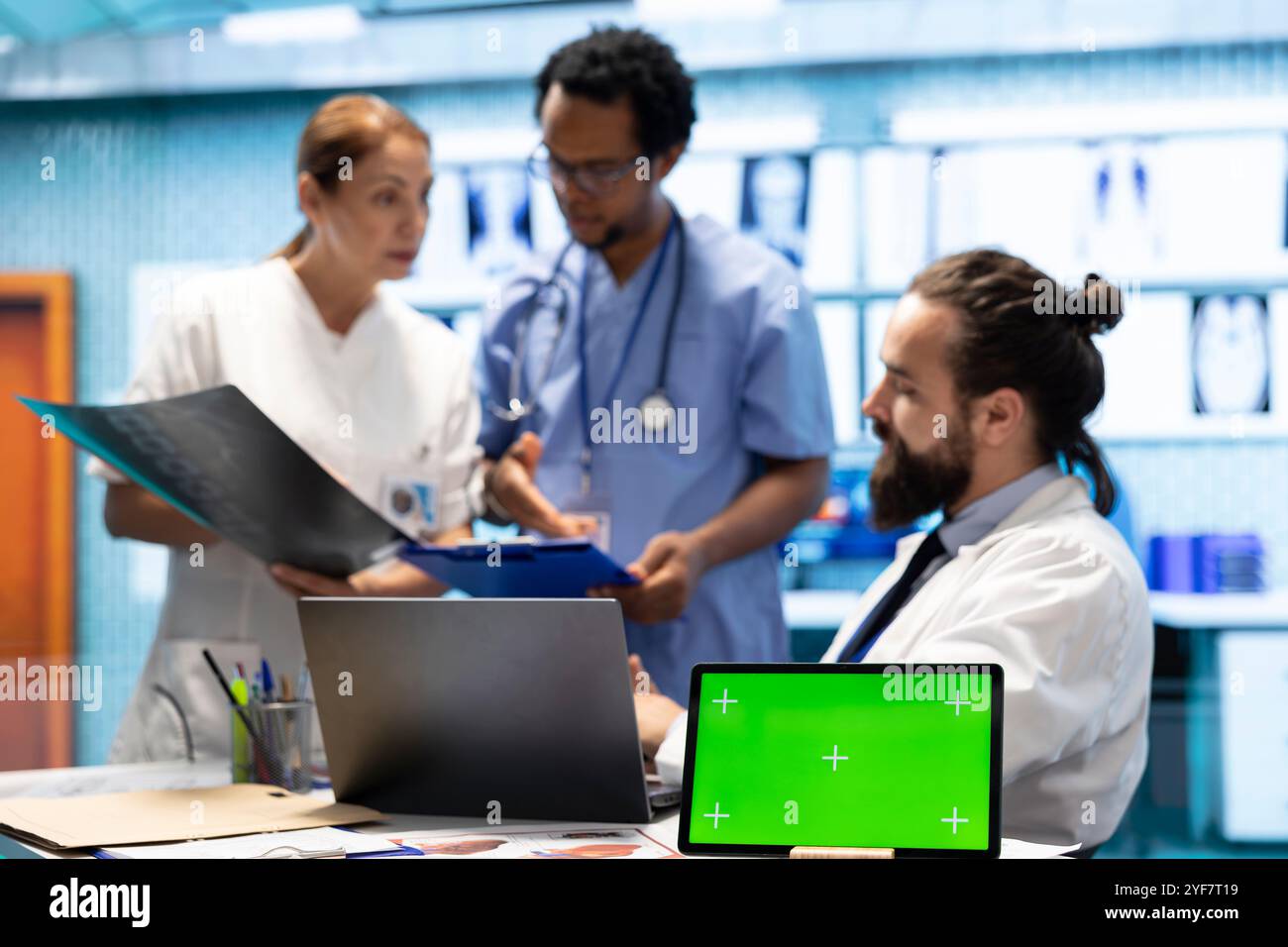 Team of doctors consulting analytics next to green screen on laptop in ...