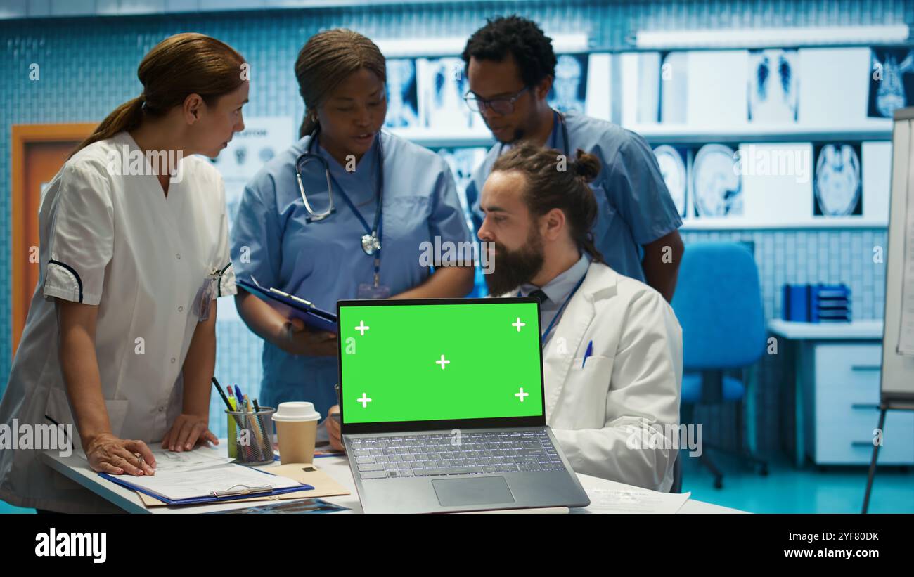 Team of doctors consulting analytics next to green screen on laptop in ...