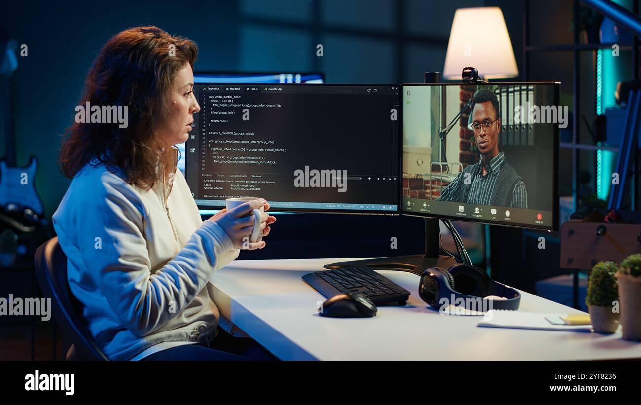 Software engineer teacher doing online tutoring, talking with student in online videocall about ways to do debugging. IT master teaching apprentice in webinar how to write code, camera A Stock Photo