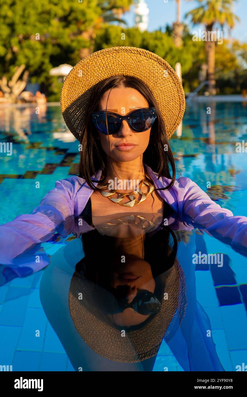 Stylish Woman with Straw Hat Relaxing in the Pool at Sunset Stock Photo ...