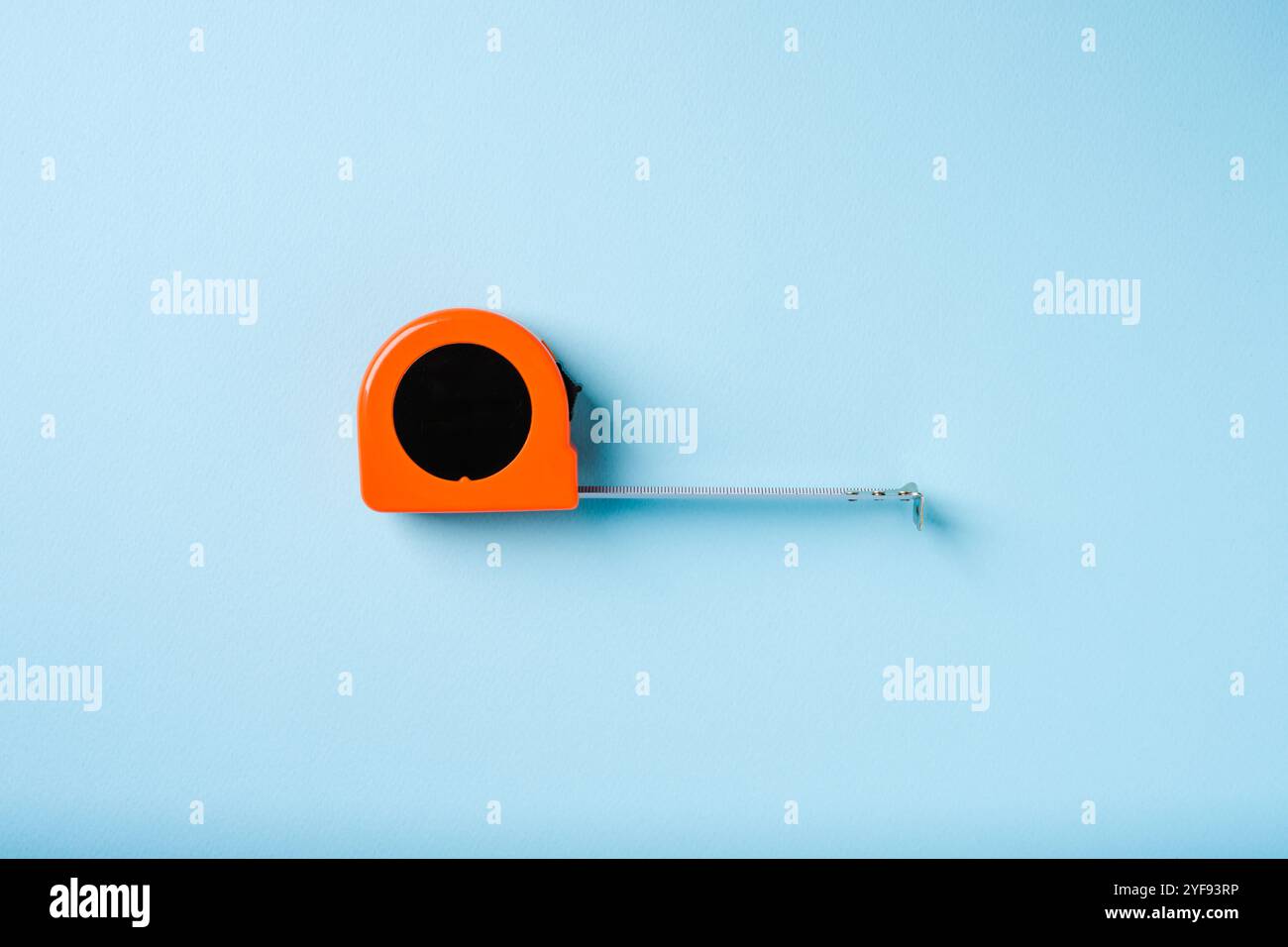 Orange retractable tape measure on blue background Stock Photo