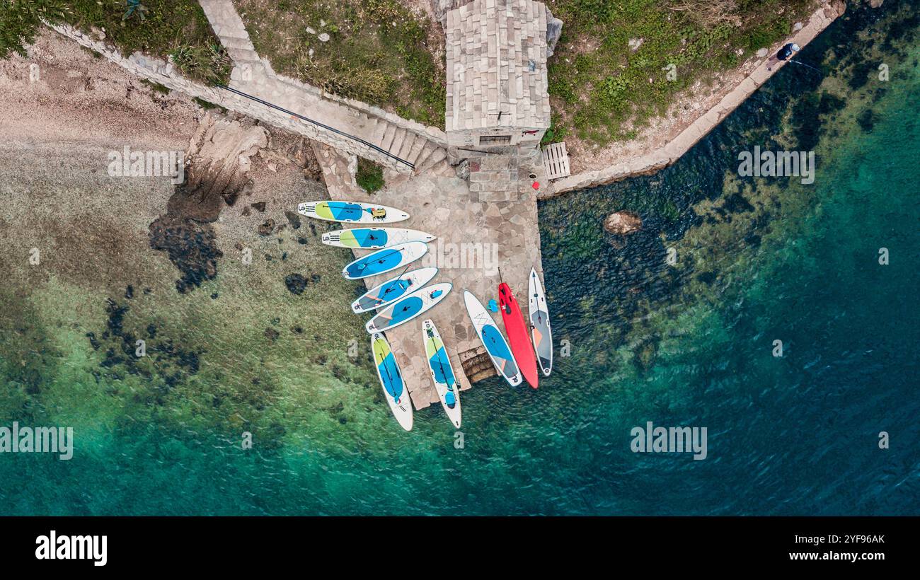 aerial view of colorful stand-up paddleboards lined up on a serene beachfront Stock Photo