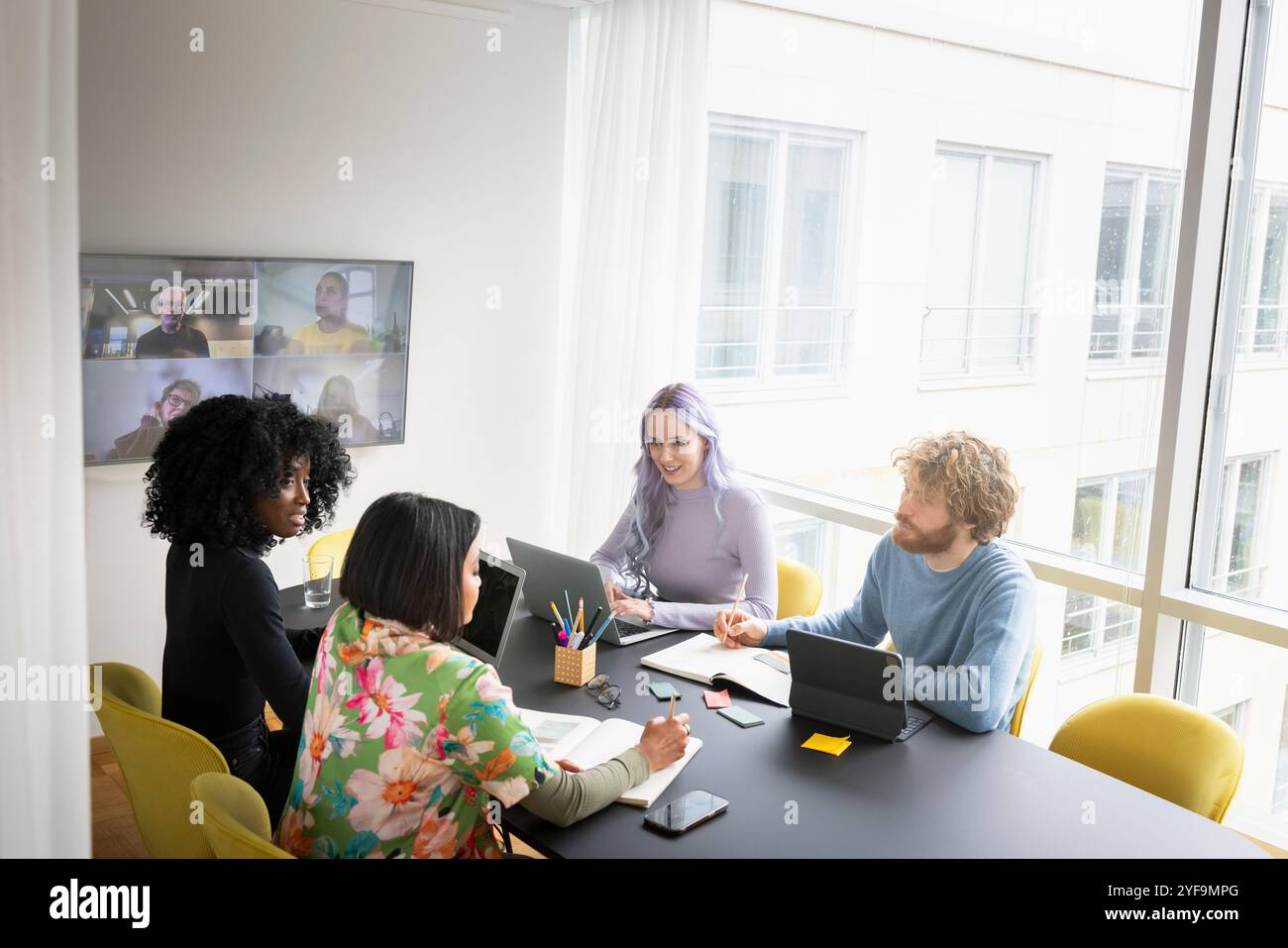 Male and female entrepreneurs discussing while sitting in conference room Stock Photo