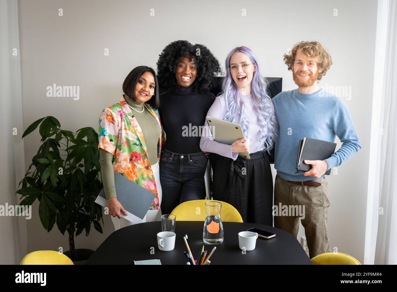 Portrait of happy male and female business professionals standing with each other in conference room Stock Photo