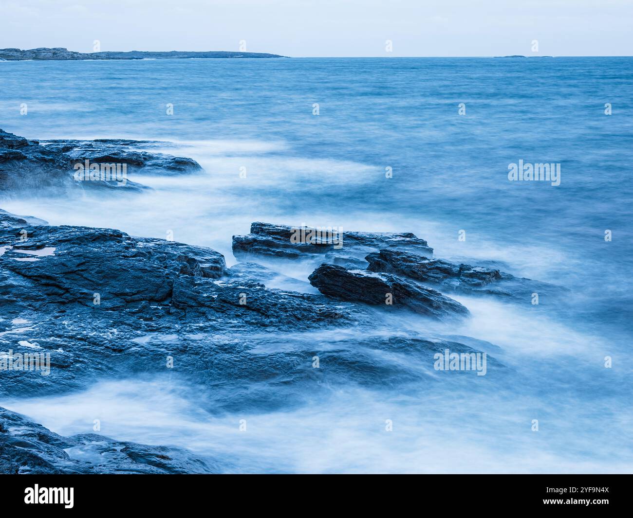 Waves breaking on rocks in sea Stock Photo