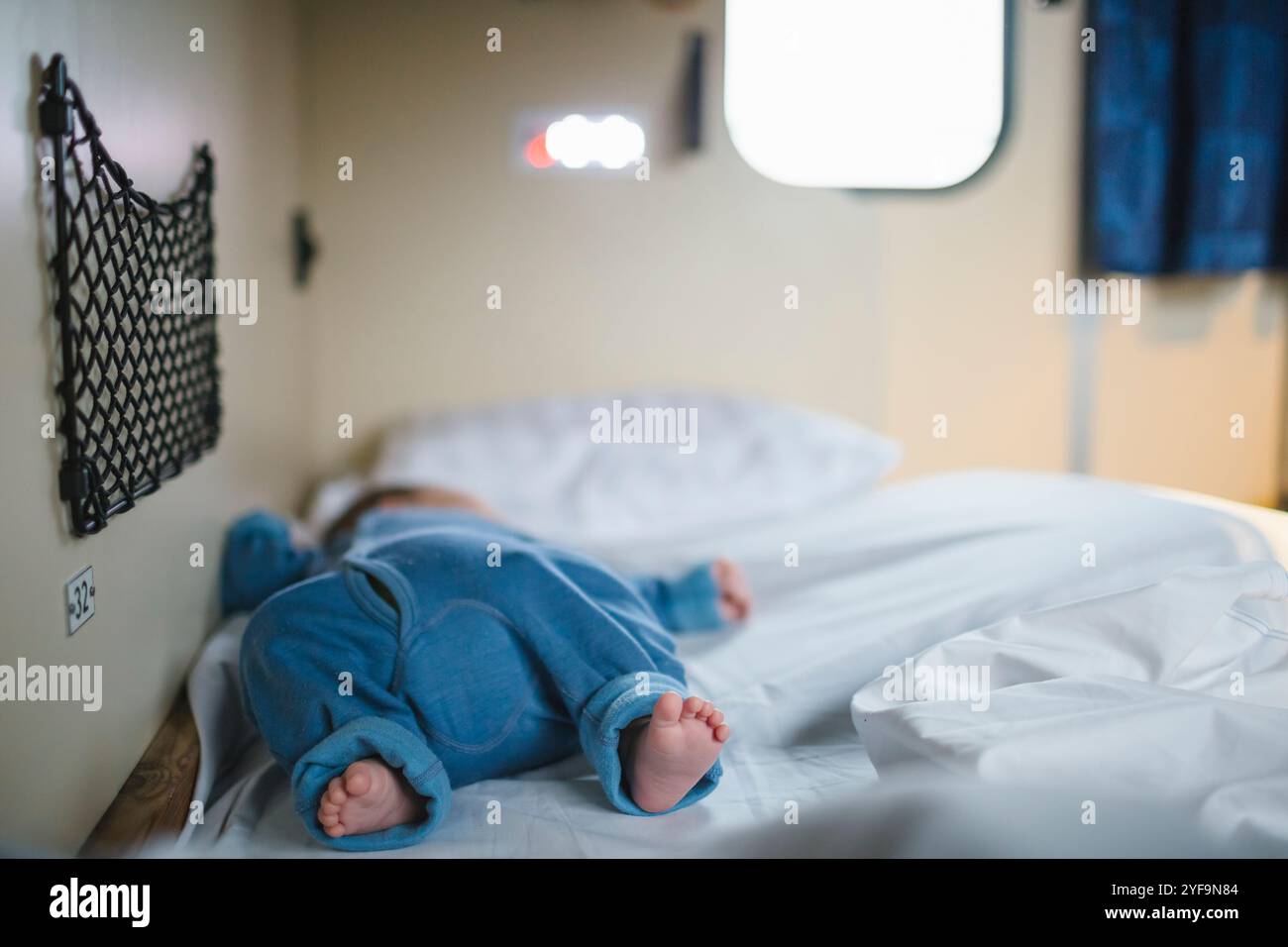 Boy with barefoot sleeping on bed in sleeper train Stock Photo