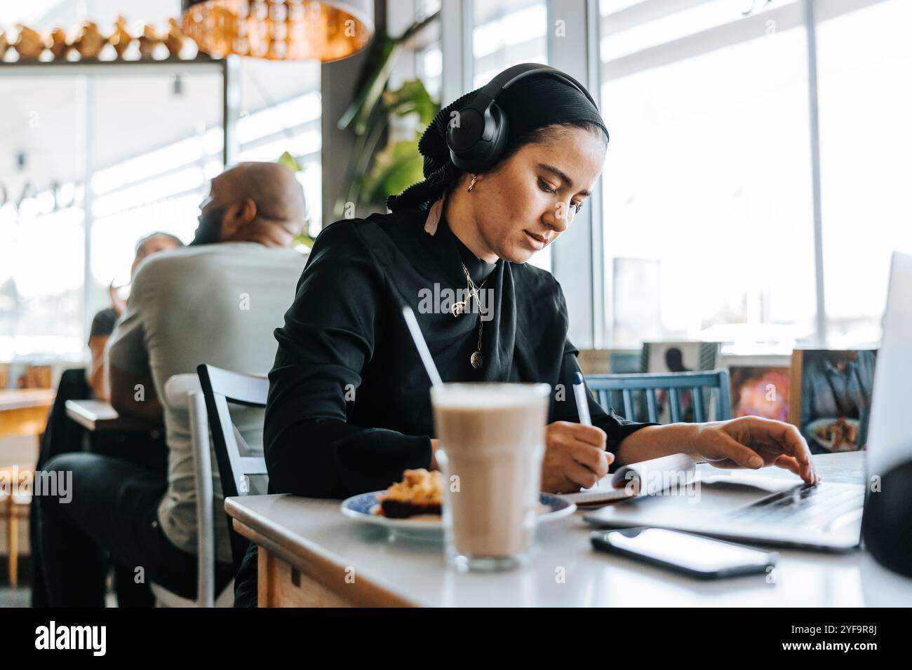Young woman freelancing while sitting in cafe Stock Photo