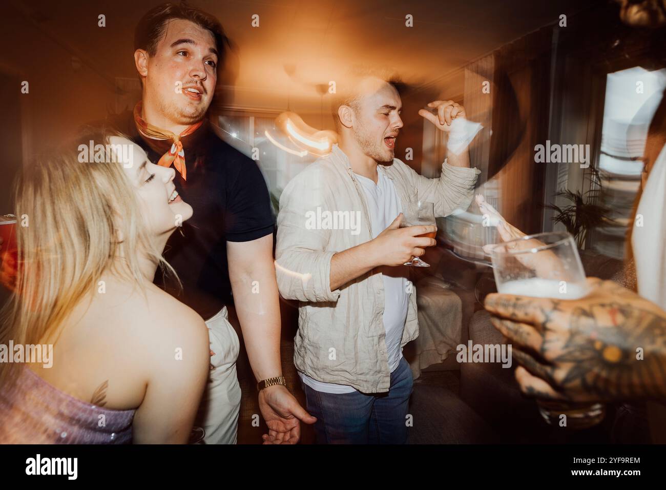 Friends enjoying drink while dancing at party Stock Photo