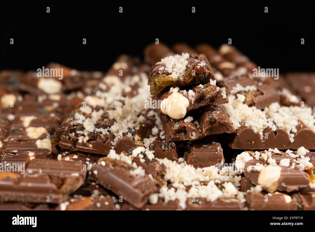 Pieces of broken organic milk chocolate with nuts and raisins. Healthy sweets Stock Photo