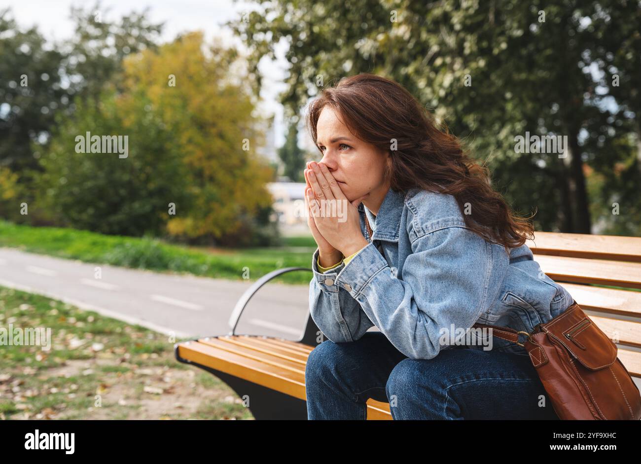 Frustrated  city woman sitting on bench in city park. Mental illness, problems, worries. Stock Photo