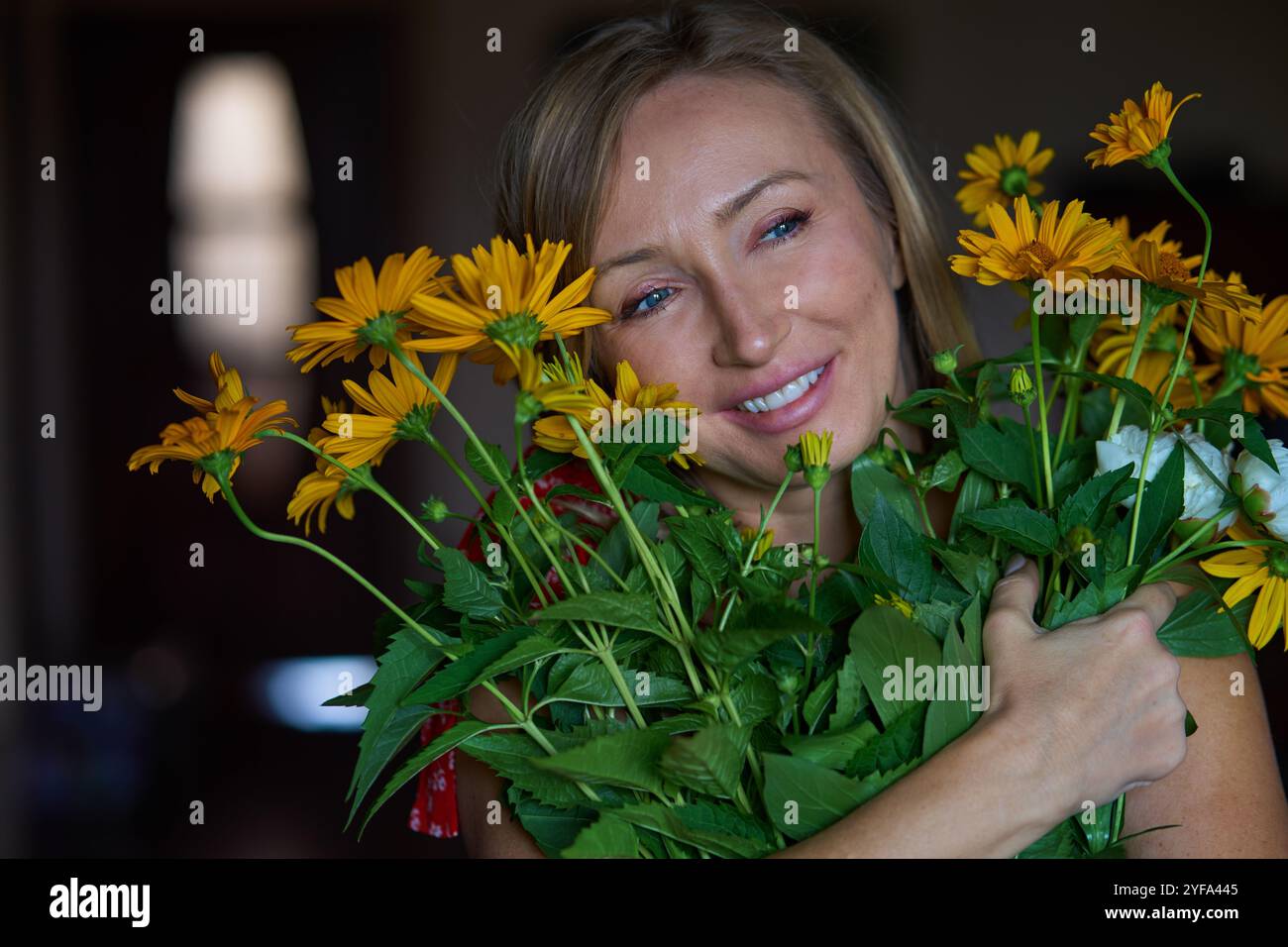 Carefree smiling blond woman holding bunch of flowers Stock Photo - Alamy