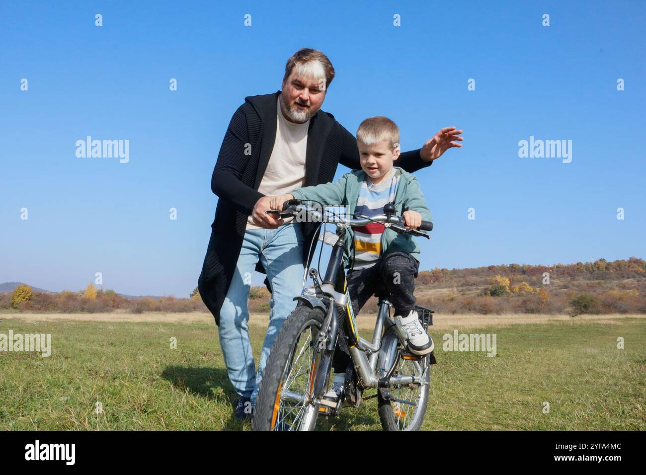 Learning to ride: a fun father-son experience Stock Photo