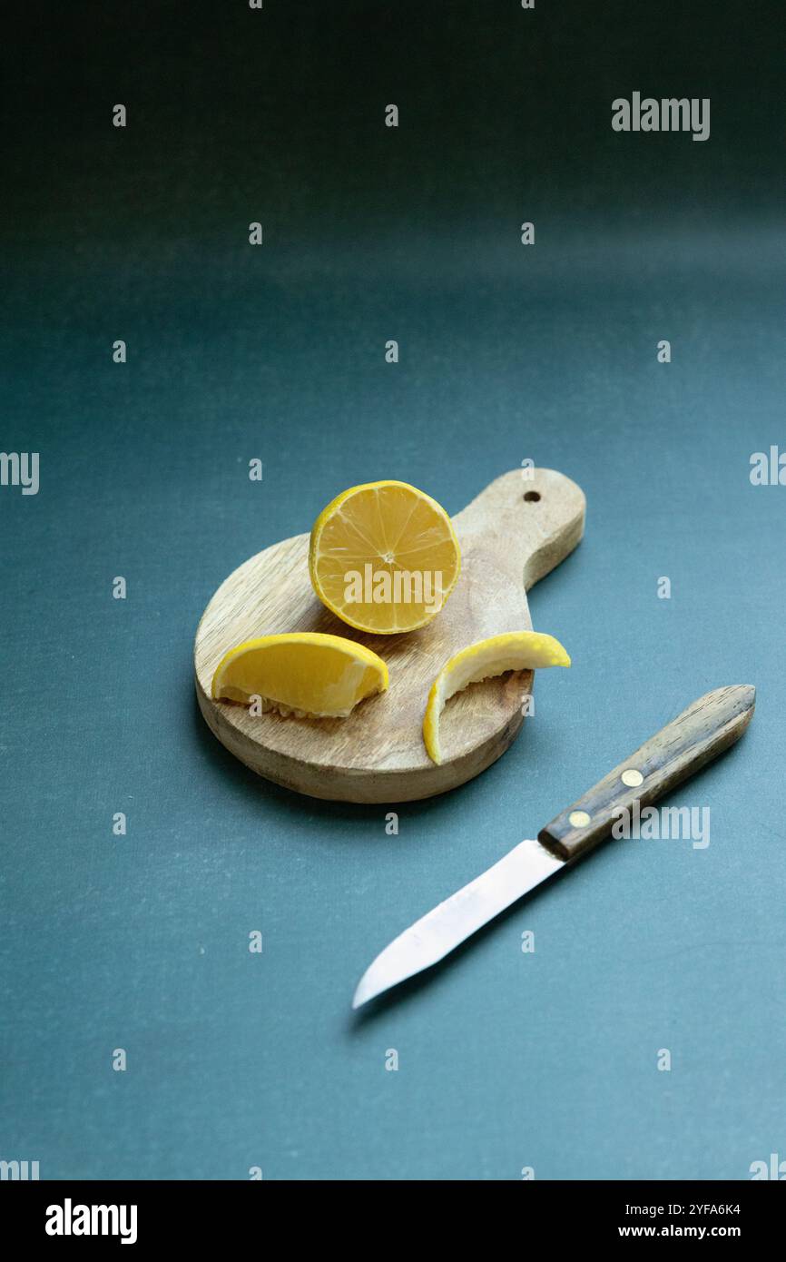 sliced lemon on rustic cutting board against green background Stock Photo