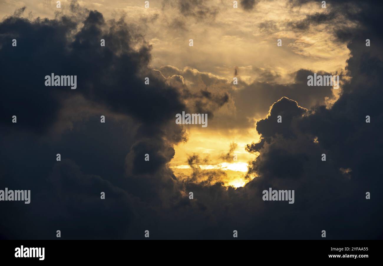 Sun behind dark clouds. Dramatic sunrice in winter. Stormy black clouds Stock Photo