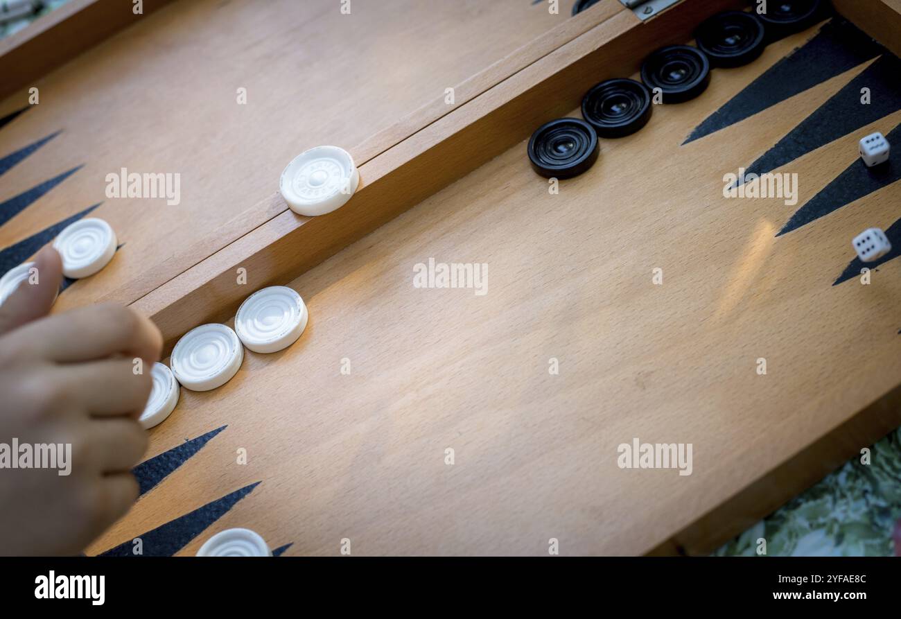 Hand throwing dice on a wooden backgammon board playing backgammon game Stock Photo