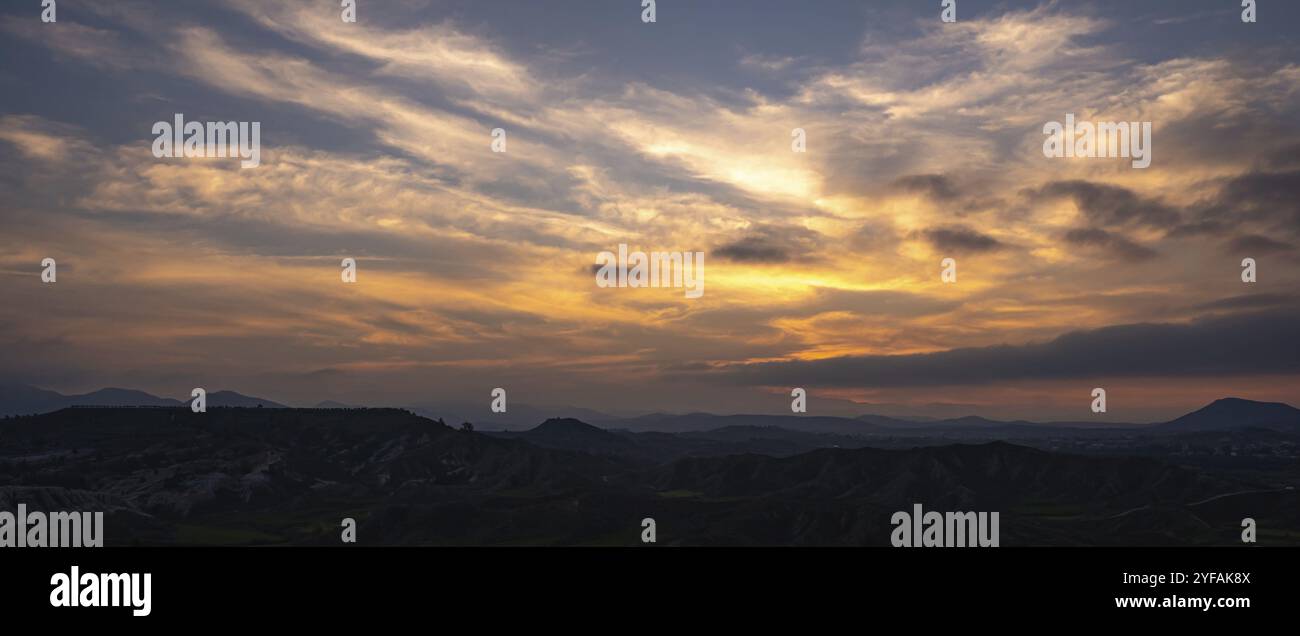 Sunset over the mountains with dramatic clouds. Panoramic mountain landscape at dusk Stock Photo