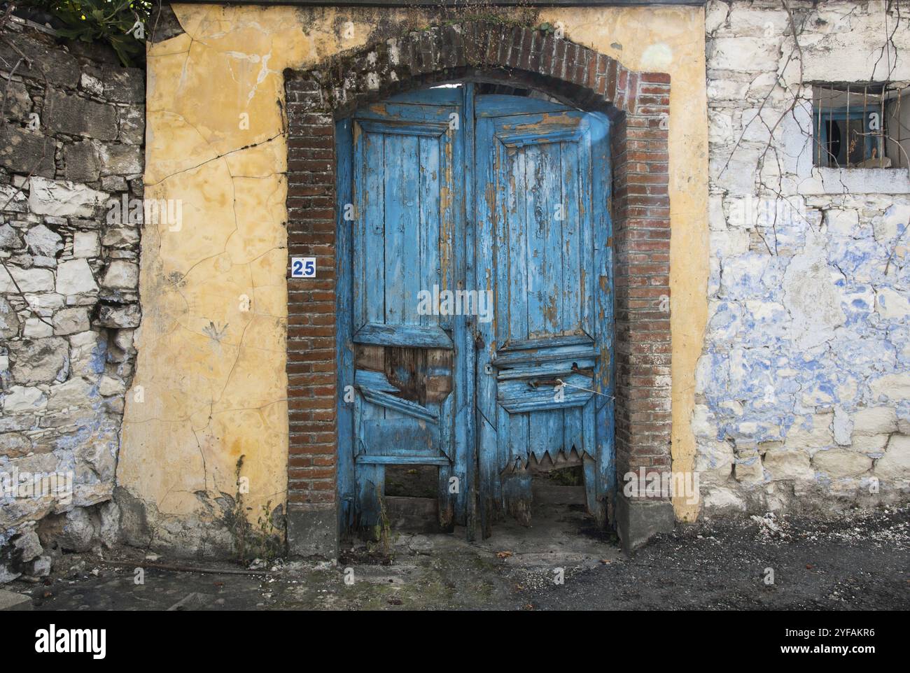 Entrance of an abandoned house with a blue damaged wooden door from a ...