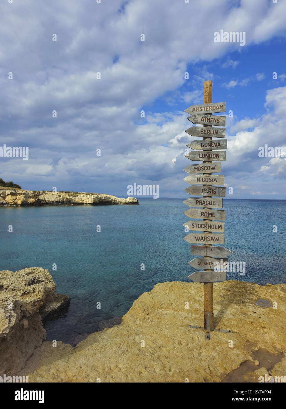 Signpost of direction of European capital cities on a wooden board in the coast against cloudy sky Stock Photo
