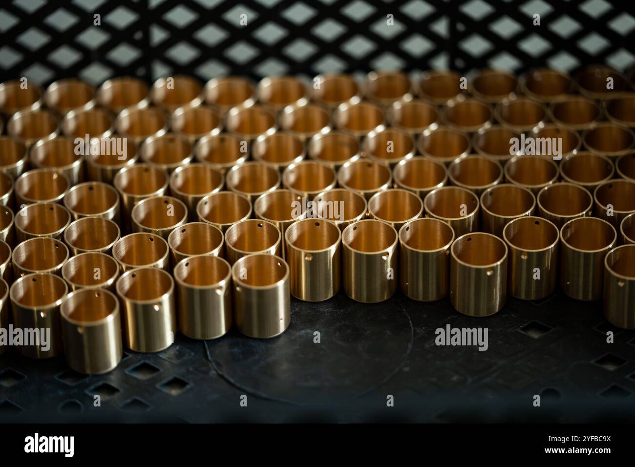 A collection of small brass cylinders organized in a tray, highlighting the uniformity and precision of manufacturing. Stock Photo