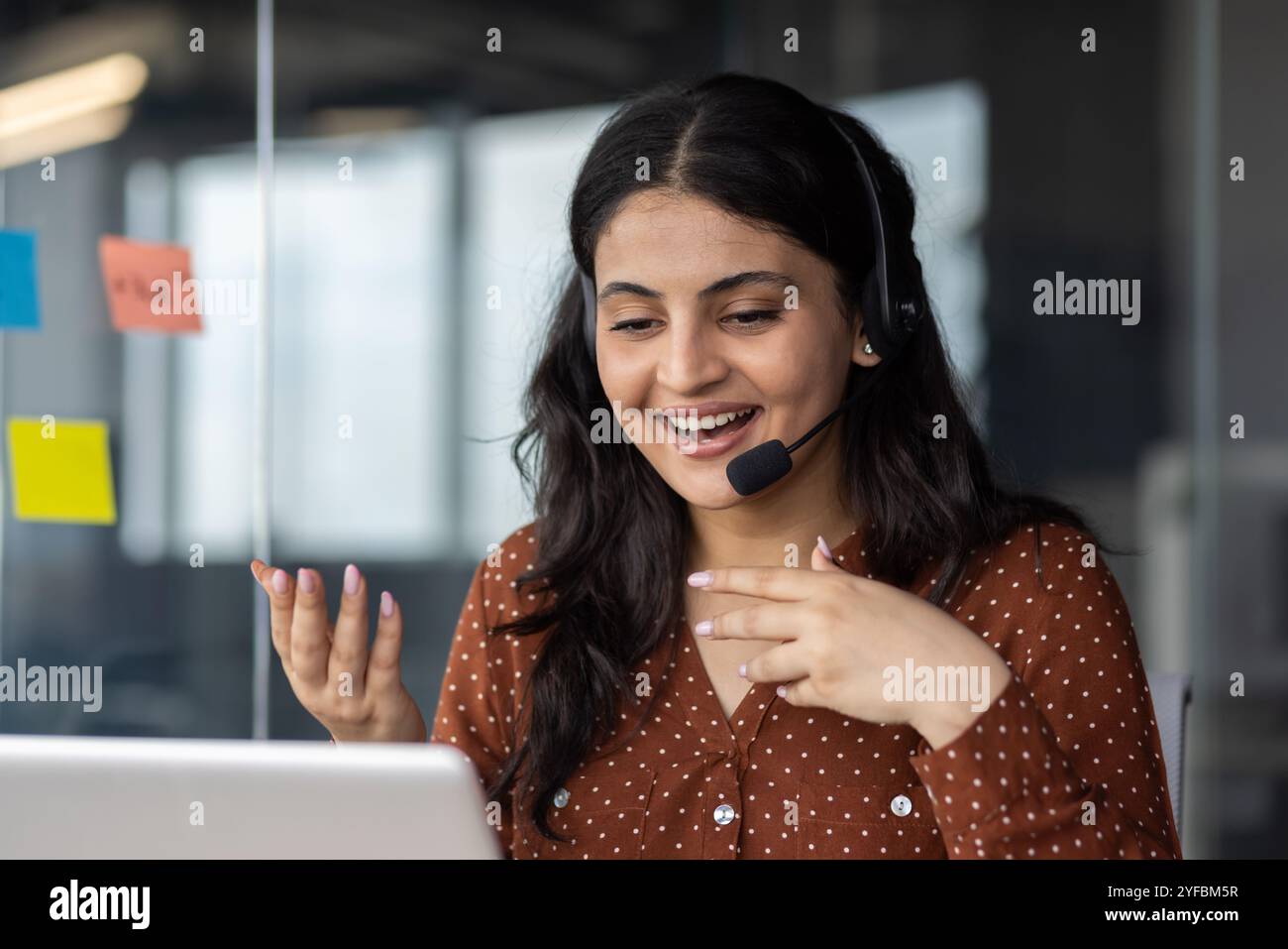 Young hispanic business woman using headset during online meeting ...