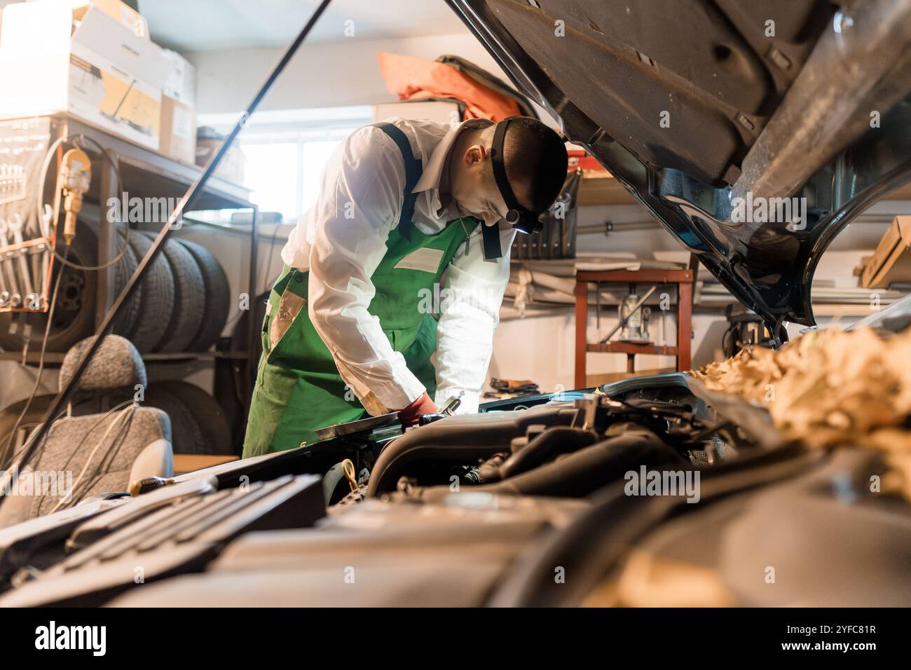 Mechanic Working on a Car Engine in a Workshop. Stock Photo