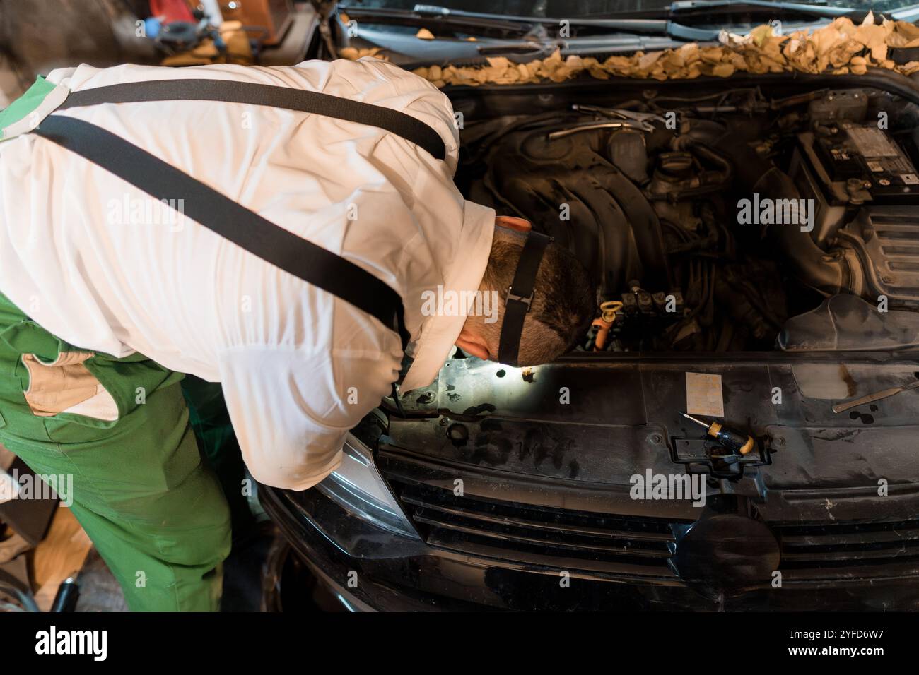Mechanic Inspecting Engine Components in a Dimly Lit Garage Stock Photo ...