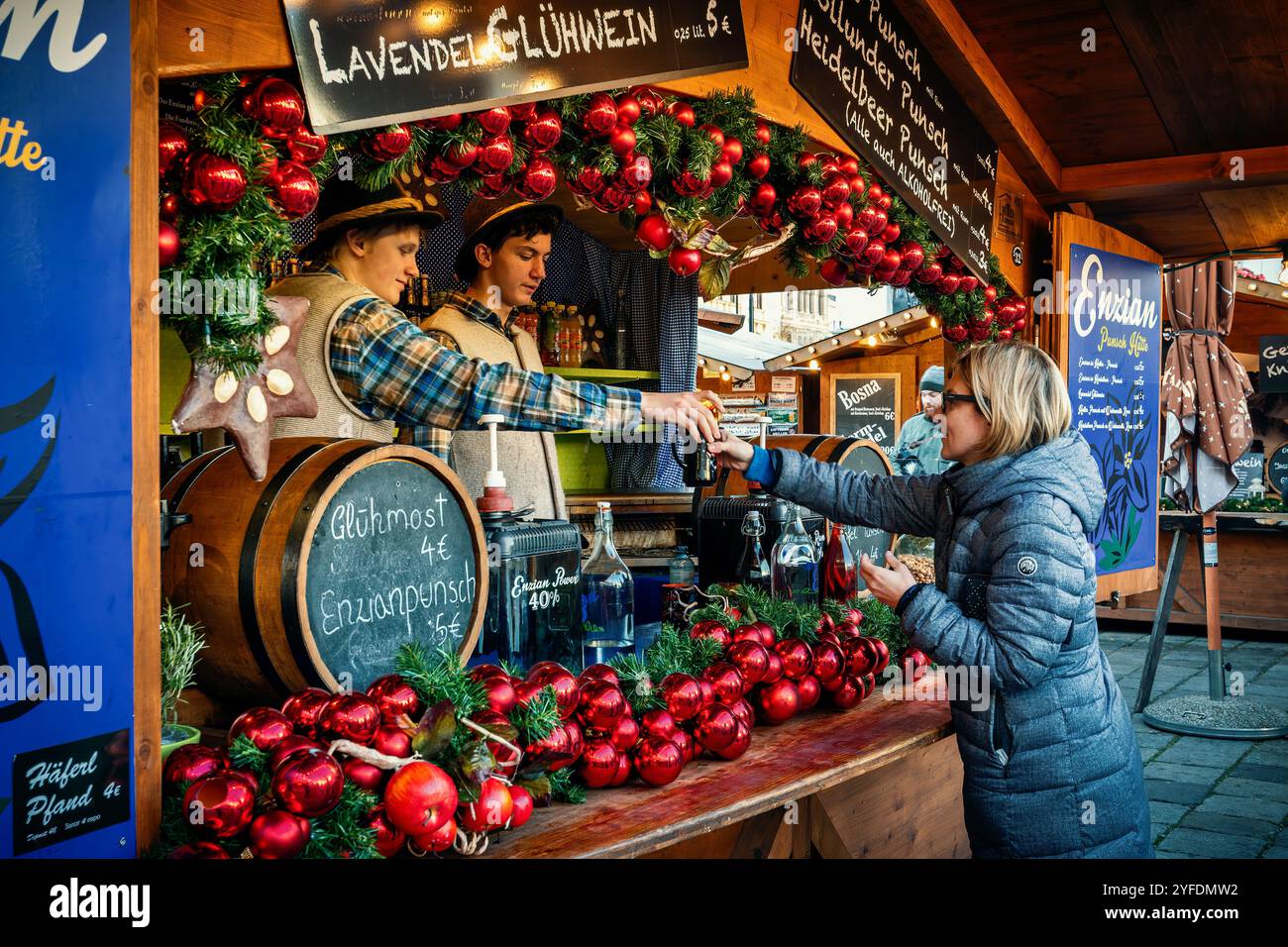 Woman buys hot mulled wine from wooden kiosk at annual Christmas market in Vienna, Austria. Stock Photo