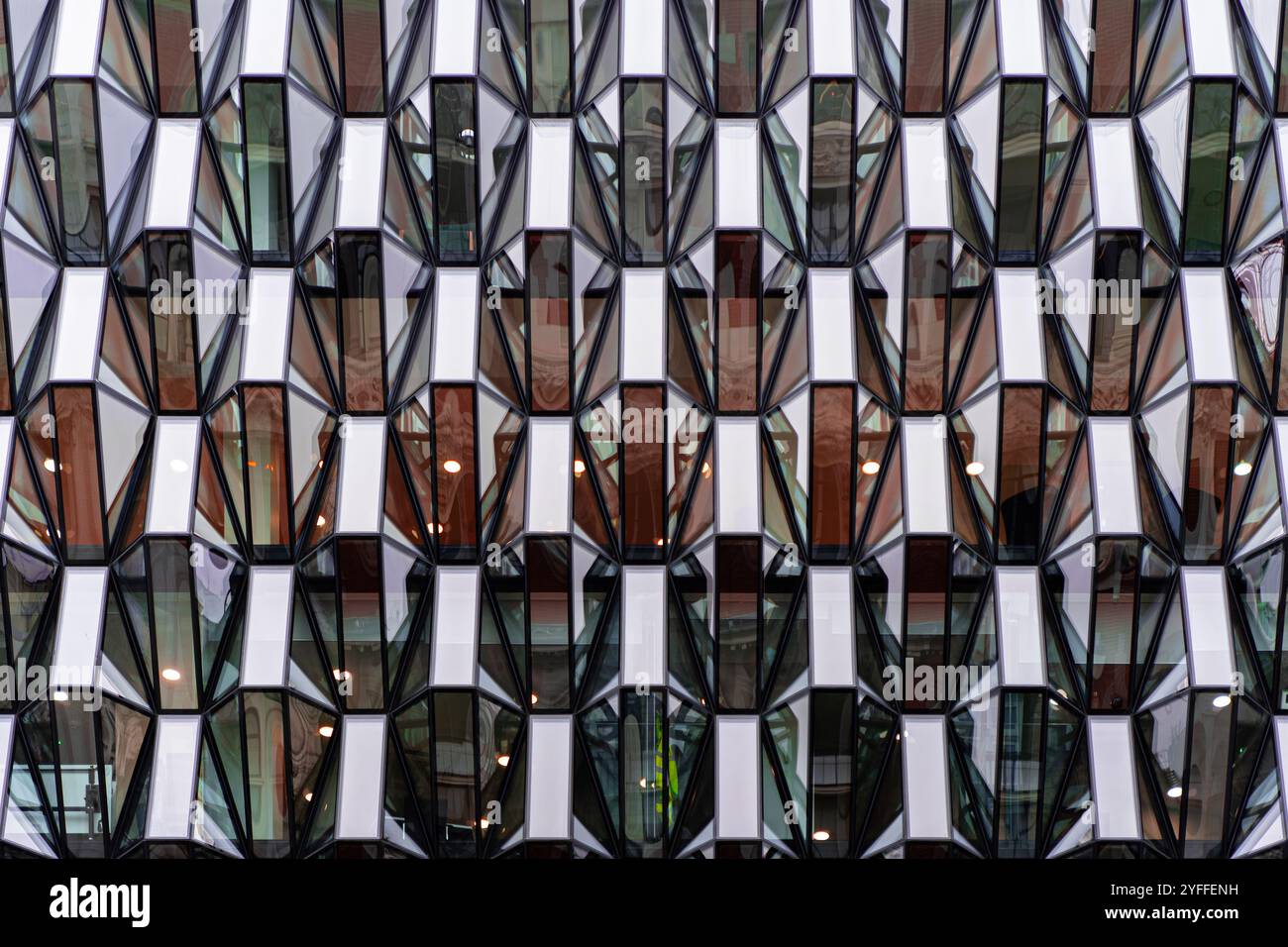 Modern Geometric Glass Facade of Urban High-Rise Building with Symmetrical Architectural Patterns and Reflections Stock Photo