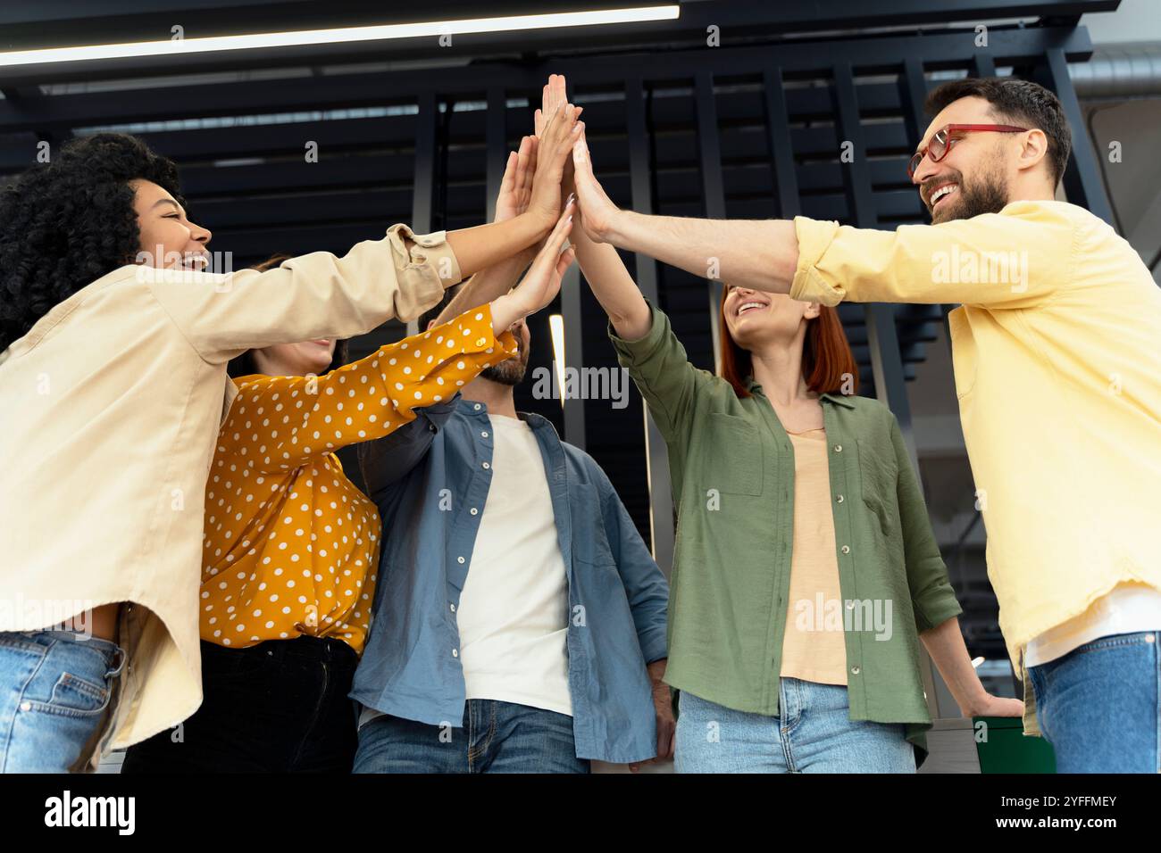 Team of diverse colleagues is celebrating success by giving a high five ...