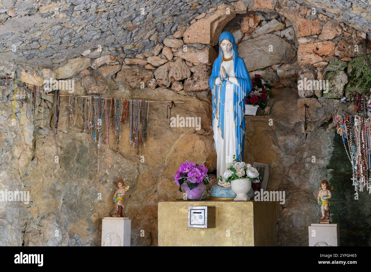 Our Lady of Lourdes – a statue in a grotto near the Church of the Sacred Heart of Jesus in Studenci, Bosnia and Herzegovina. Stock Photo