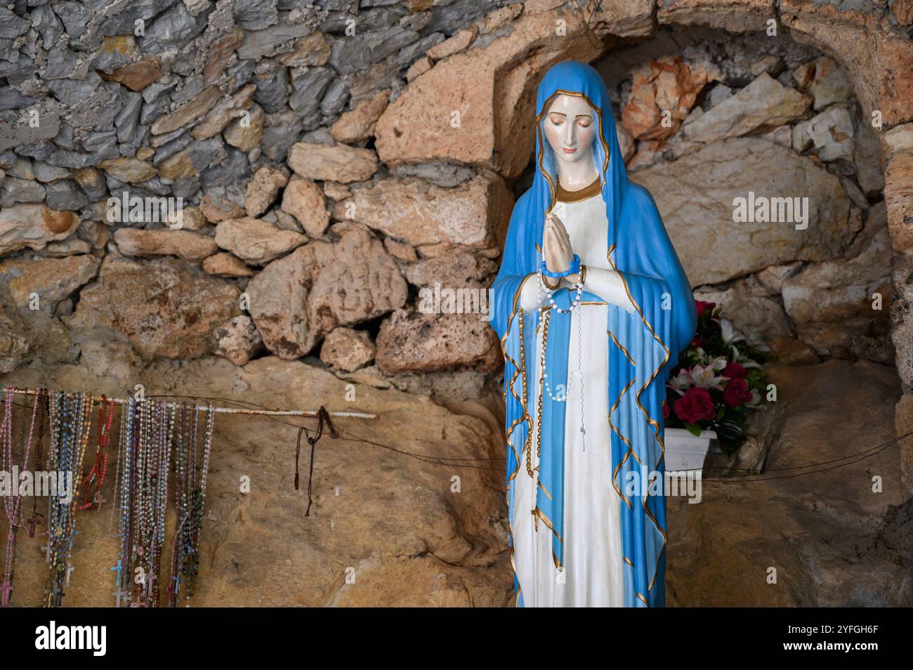 Our Lady of Lourdes – a statue in a grotto near the Church of the Sacred Heart of Jesus in Studenci, Bosnia and Herzegovina. Stock Photo