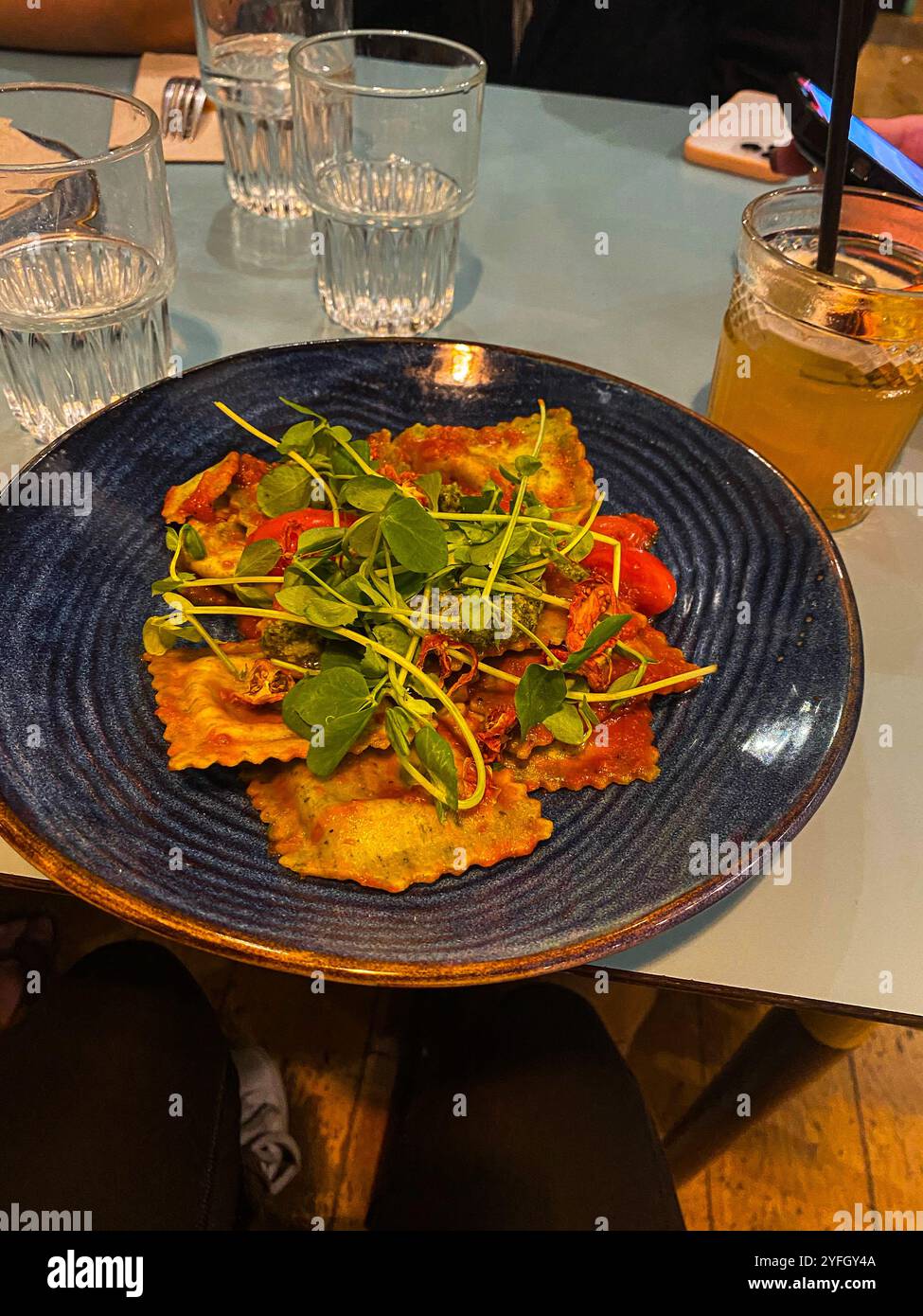 Gourmet Ravioli Dish with Refreshing Drink at a Restaurant Table - Smartphone Captured Stock Image
