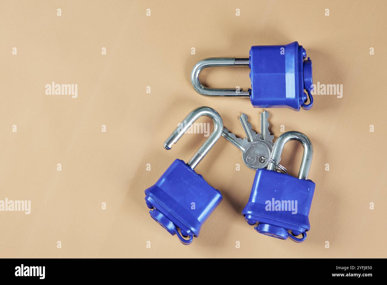 Padlock with blue plastic insulation and key, on a beige background ...