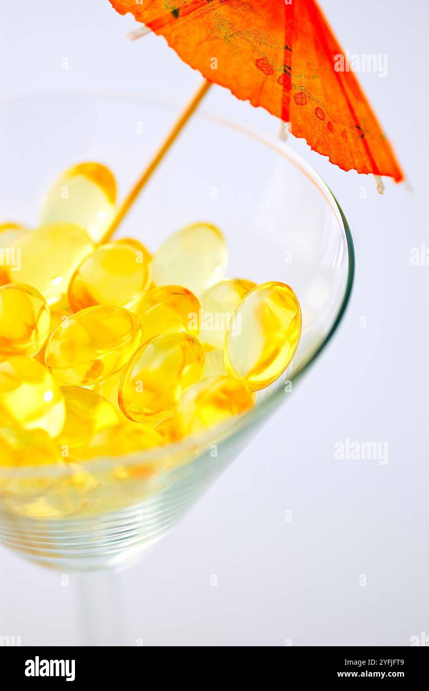 Macro of cod liver fish oil supplement capsules in a martini glass over white background Stock Photo