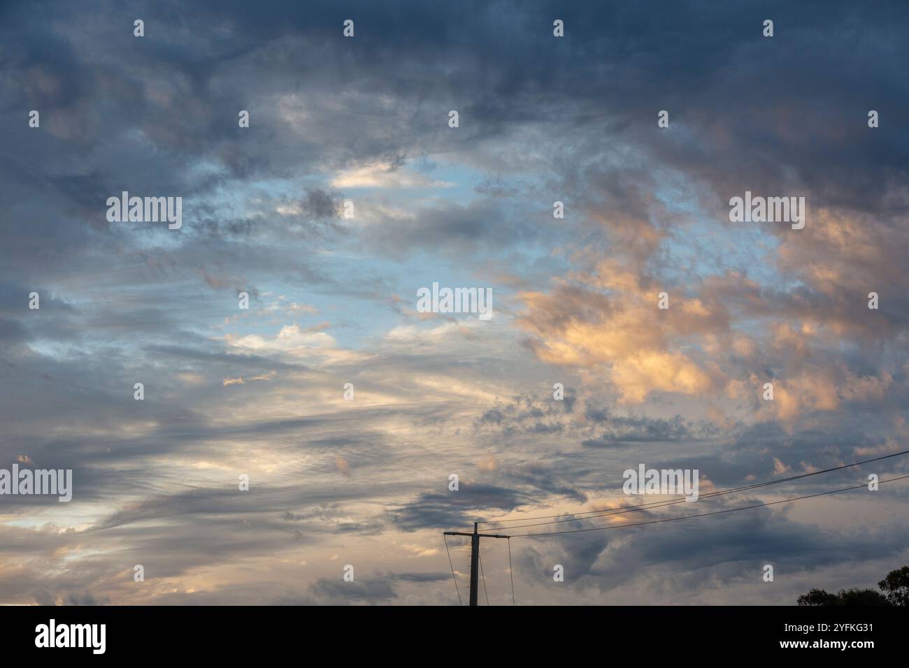 Dramatic, sunset skies with layers of cloud swirling and blue and pink highlights across clouds. Stock Photo
