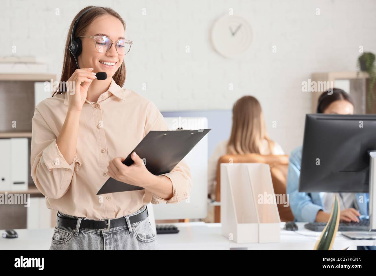 Female technical support agent with headset and clipboard in office ...