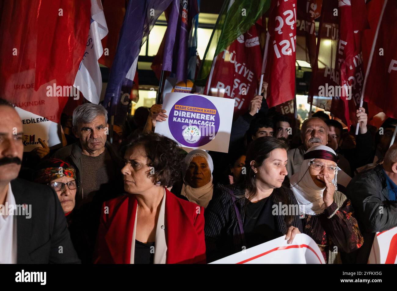 A protester holds a placard that says 'We will win by resisting against the usurpation of will' during the rally. The Official Gazette of the Republic of Turkey announced the dismissal of Mardin Metropolitan Mayor Ahmet Türk, Batman Mayor Gülistan Sönük and Halfeti Mayor Mehmet Karay?lan. The appointment of trustees to DEM (Peoples' Democratic Party) municipalities was met with protests across the country. Kurdish people and opposition political groups supporting them say it is a coup against the will of the people. In Izmir, Kurdish groups and opposition parties organized a joint protest and Stock Photo