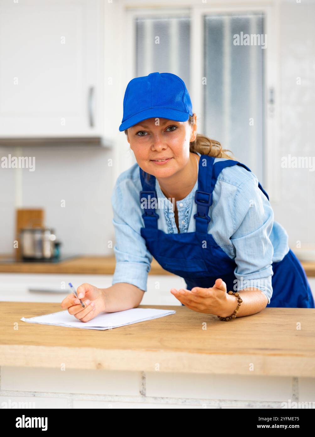 Woman house cleaner making notes in kitchen Stock Photo