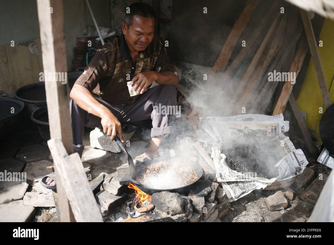 asian senior adult roasting coffee traditionally for sell at his shop Stock Photo