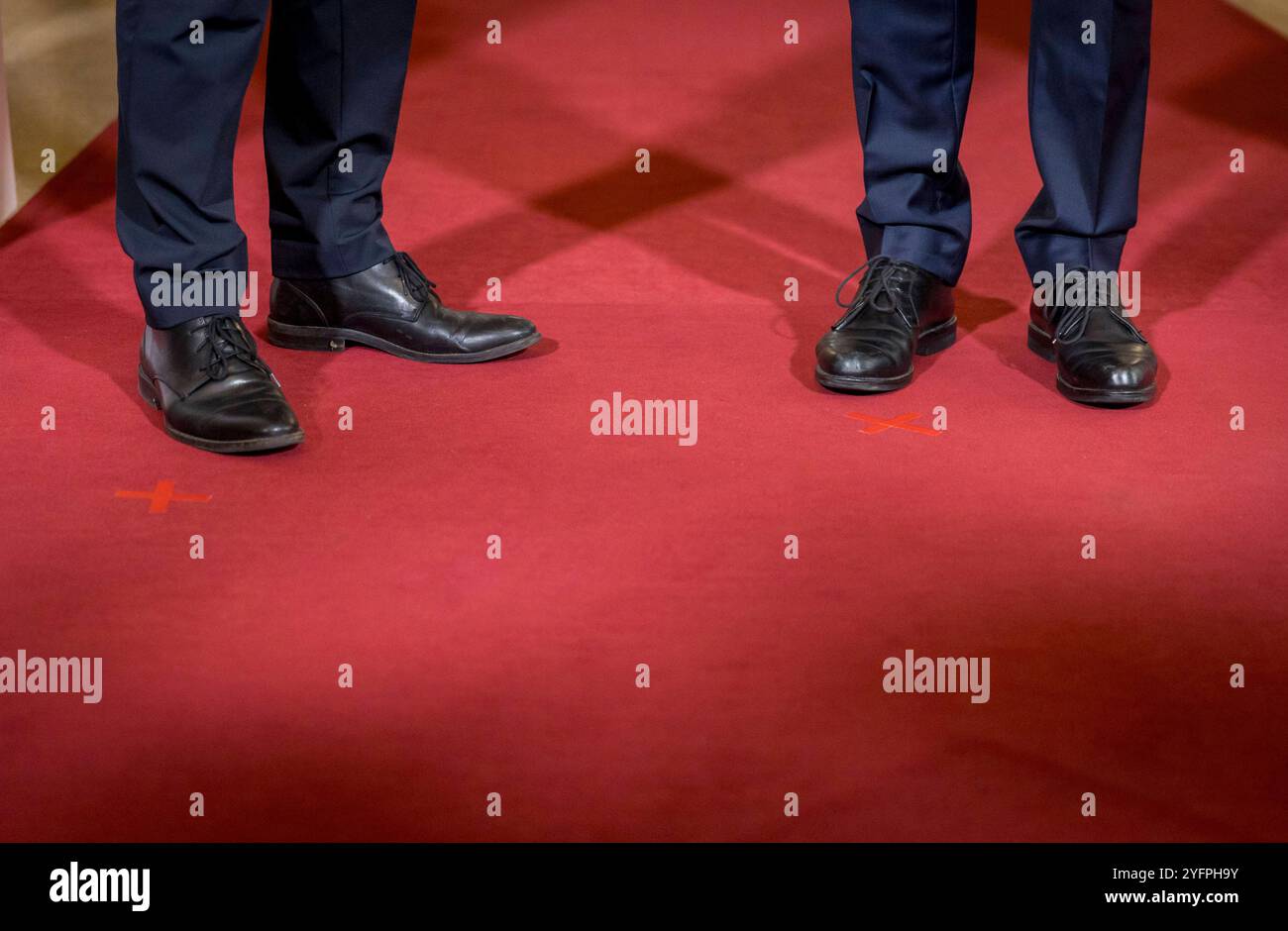 Symbolfoto zum Thema maennliche Fuehrungskraefte. Zwei Maenner im Anzug stehen auf einem roten Teppich neben zwei roten Kreuzen. Hamburg, 07.10.2024. Stock Photo