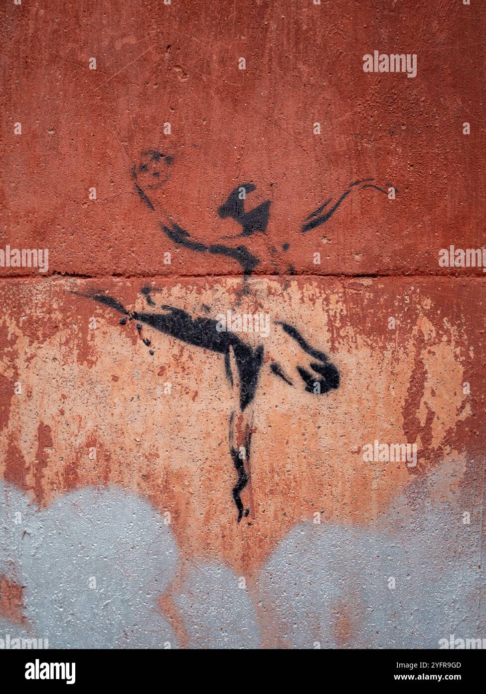 Cremona, Lombardy, Italy October 27th 2024 Black ballerina stencil graffiti art dancing on a textured red and silver wall, urban art concept Stock Photo