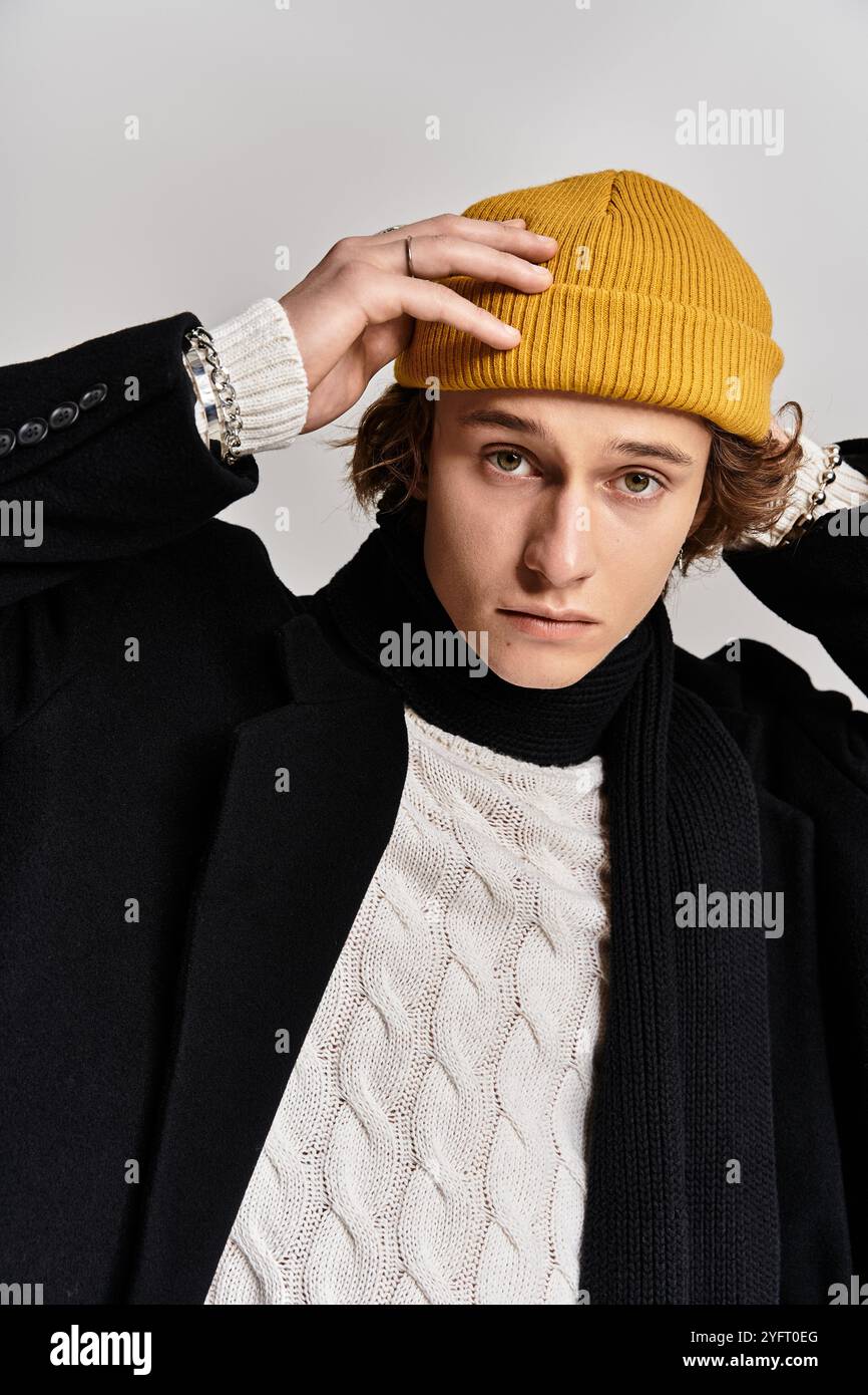 A handsome young man adjusts his yellow beanie while wearing a chic ...