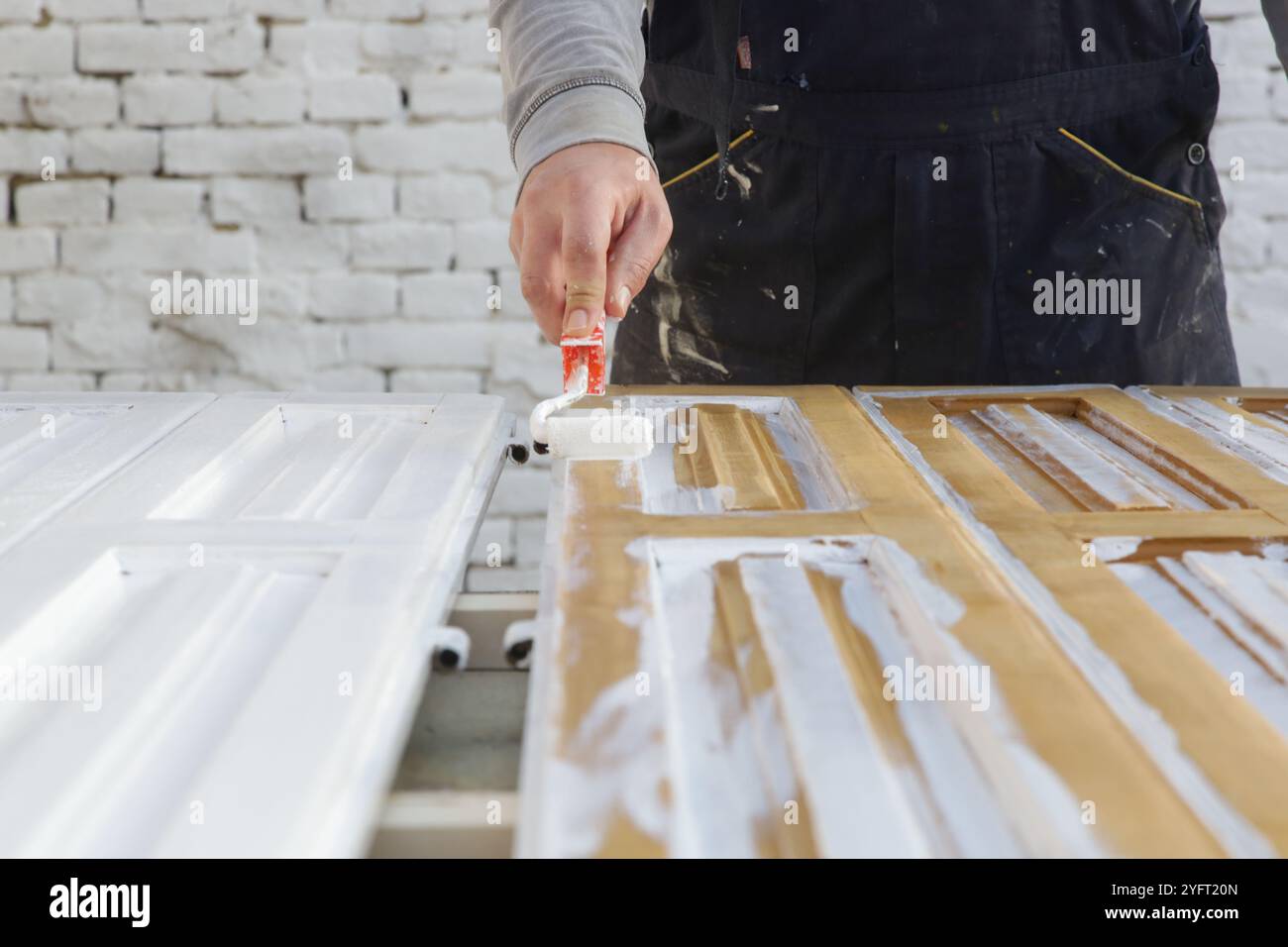 Paint roller. Process of painting with white paint over a white wooden ...