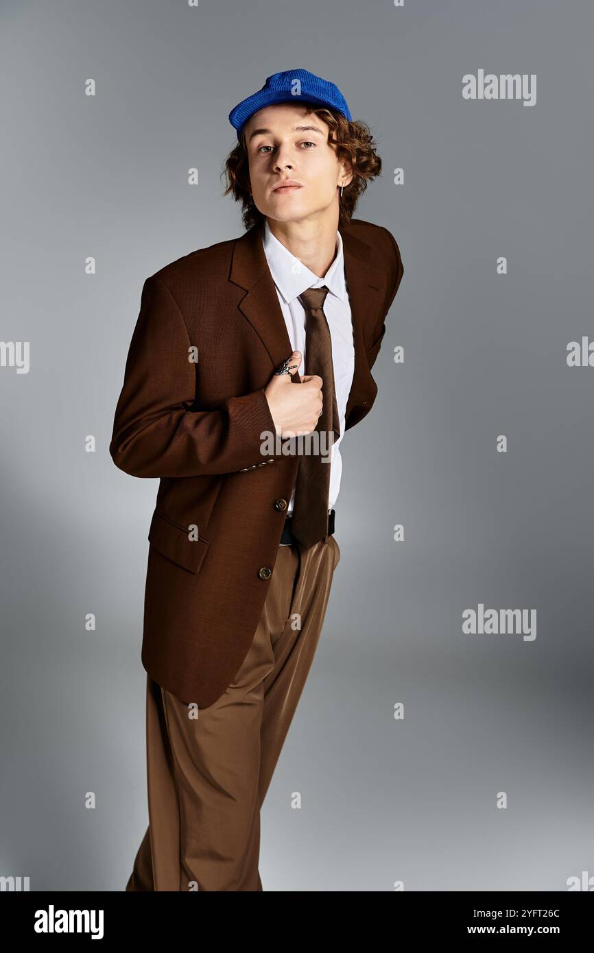 A young man dressed in a brown suit and cap confidently poses against a ...