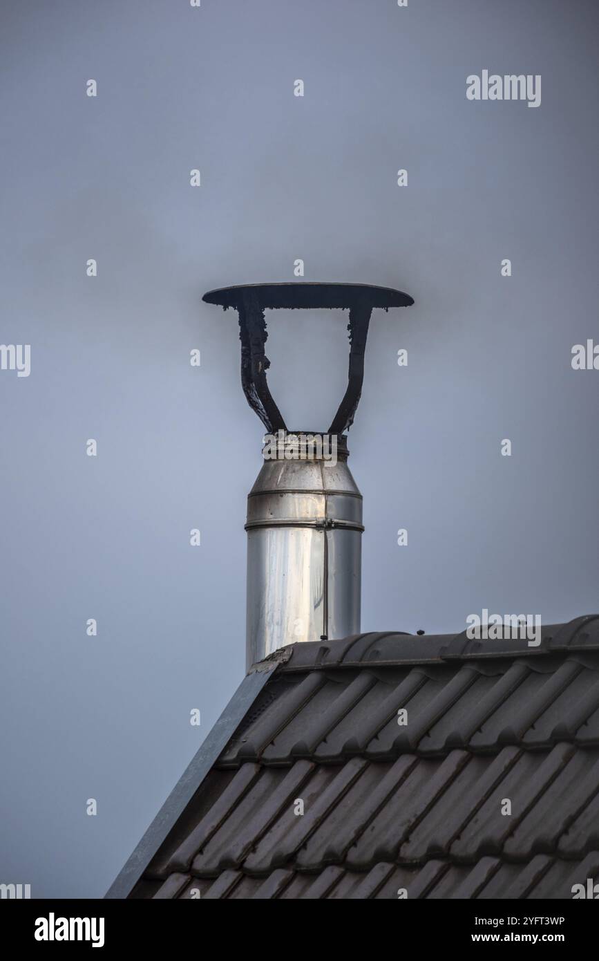 Toxic and polluting smoke coming from a chimney of a house Stock Photo