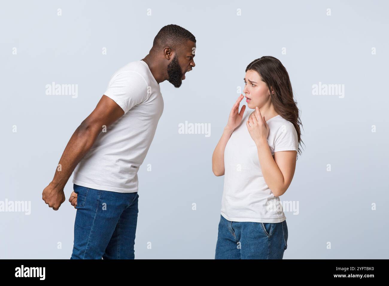 Angry afro guy emotionally shouting at his scared girlfriend, blaming her Stock Photo